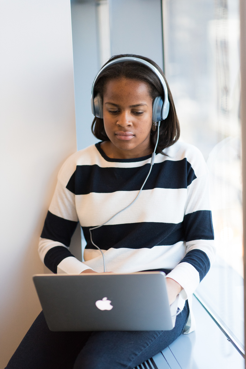 Woman Listening Through Headphones Using Macbook